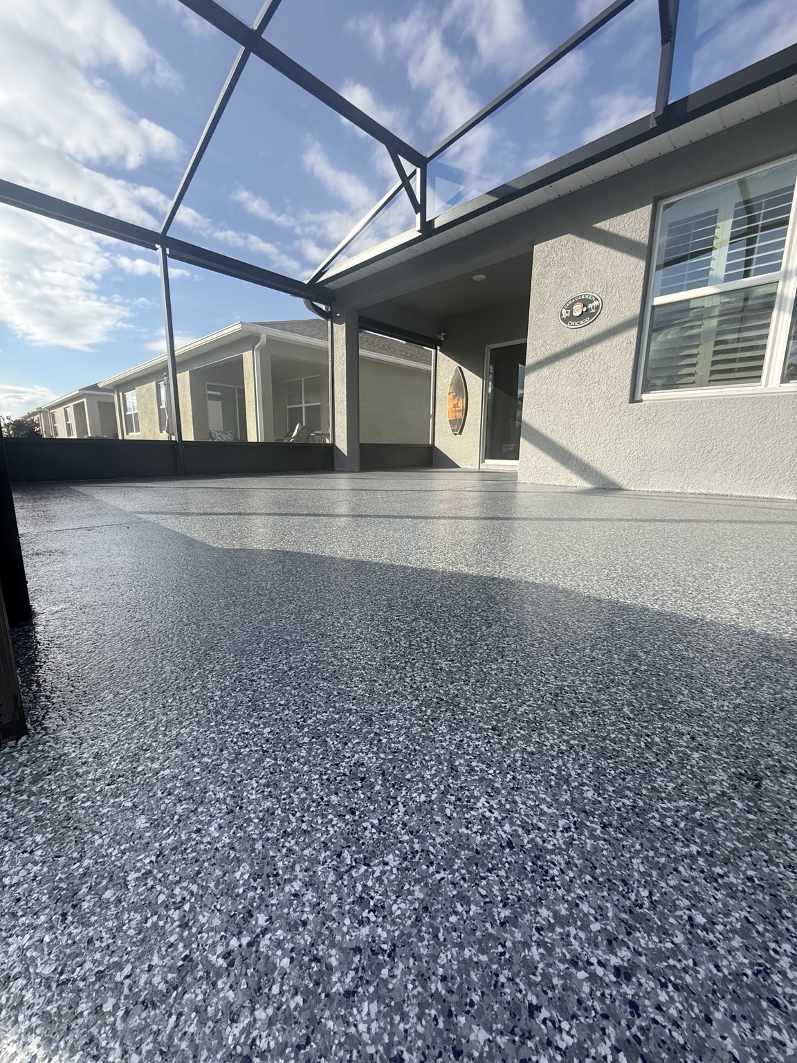 Screened lanai beside a home with a gray full-flake concrete floor coating