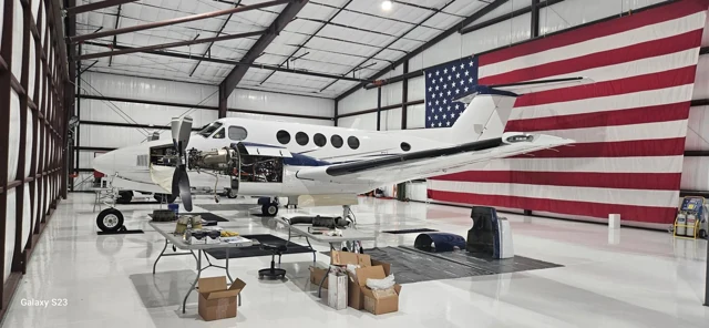 White aircraft and American flag above a reflective EpoX hangar floor