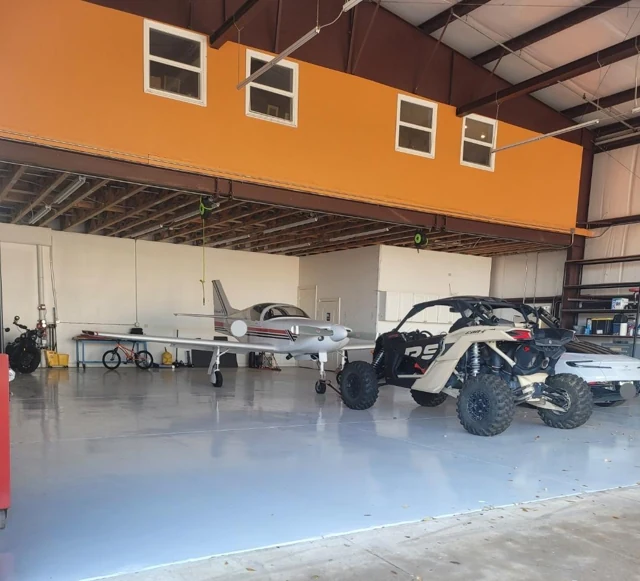 Gray EpoX hangar floor with a small aircraft and recreational vehicles